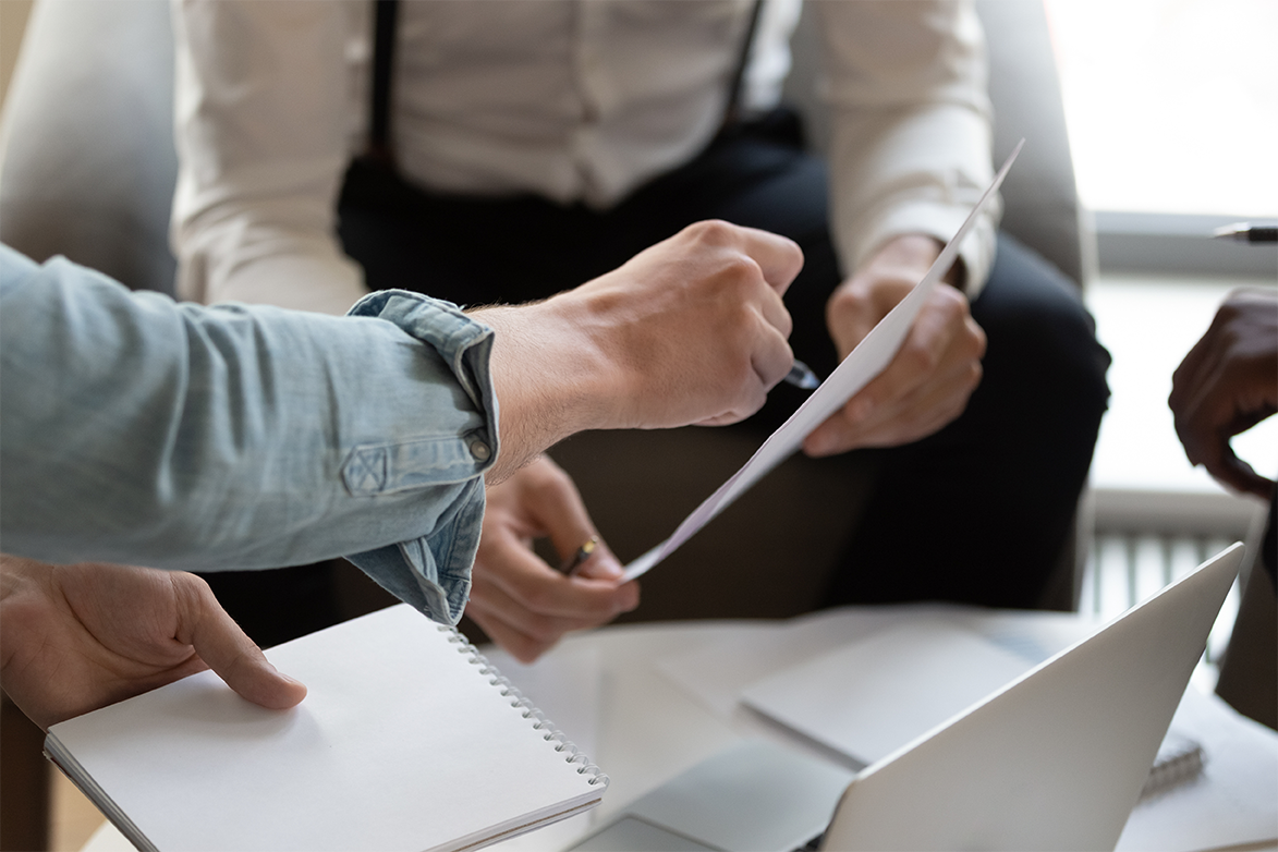 Two people are analyzing a document held in their hands. Only their hands are visible.